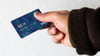 Ein Geflüchteter hält eine Debitkarte in der Hand.