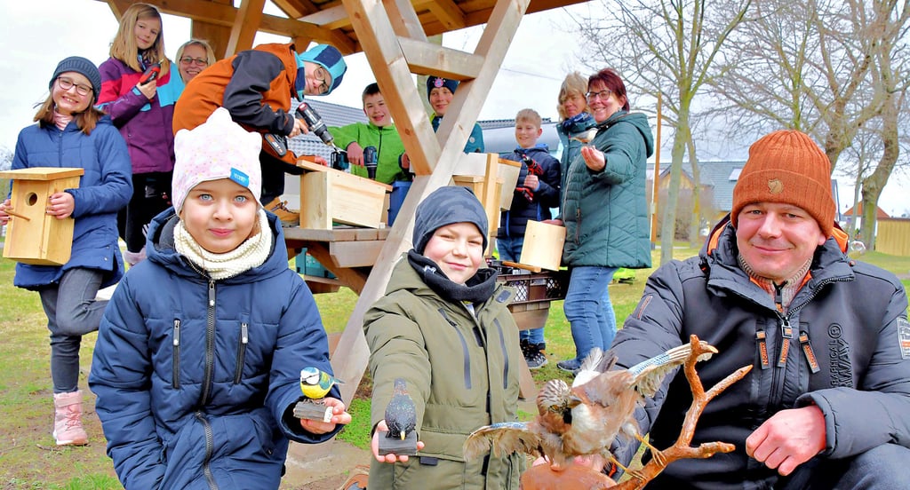 Hanni (v.l.), Lio und Andreas Bosse zeigen Modelle von Vogelarten, die im Drömling zuhause sind. Jenna (hinten; v.l.), Leonie, Janine Ahrens, Paul, Felix, Kilian, Til, Marika Tietge-Baatz und Sabine Wieter, Mitarbeiterin des Biosphärenreservats Drömling, bauen in Kathendorf Nistkästen aus Holz.