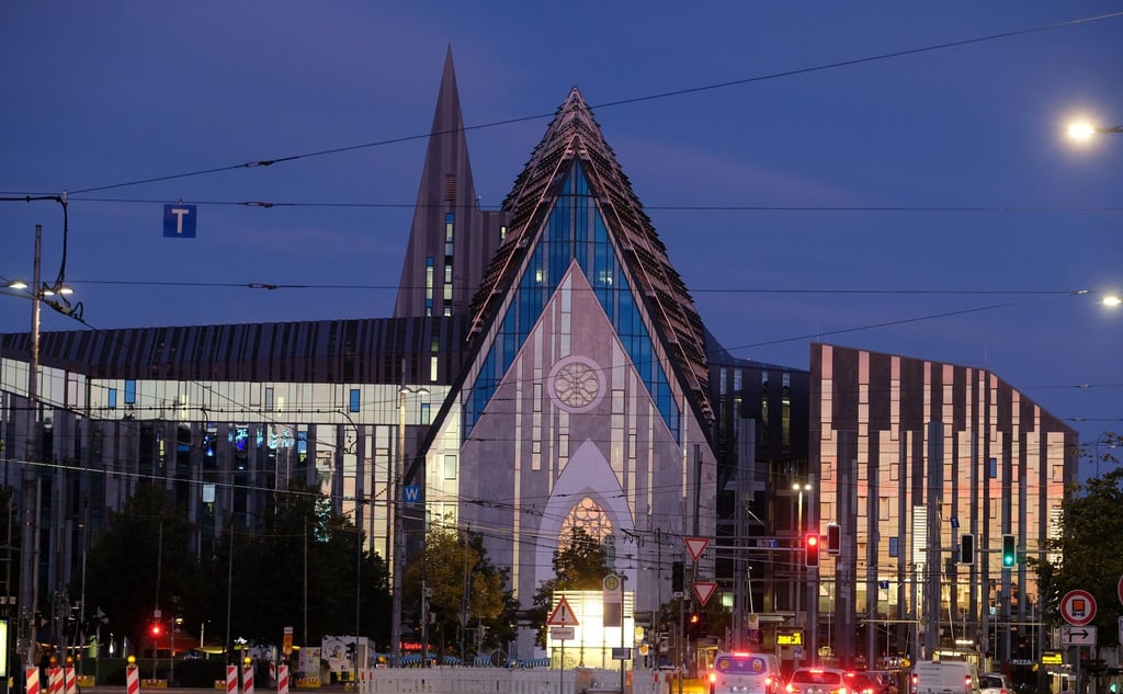 Die aufgehende Sonne wird in spiegelnden Fassadenelementen des Paulinums der Universität Leipzig reflektiert.
