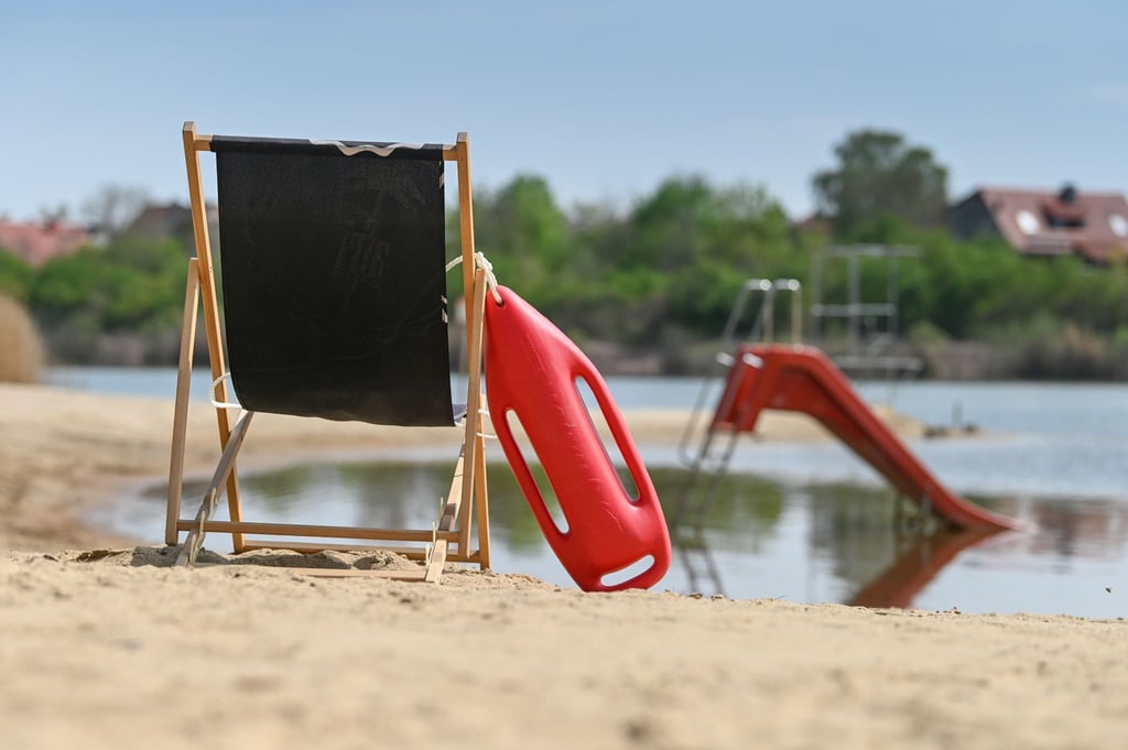 Eine Rettungsboje lehnt an einem Liegestuhl am Strand des Freibades Heidesee (Halle).