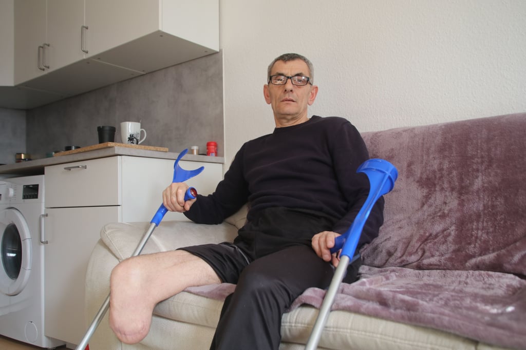 Kjamili Sherif sitzt mit seinen Krücken auf der Couch.