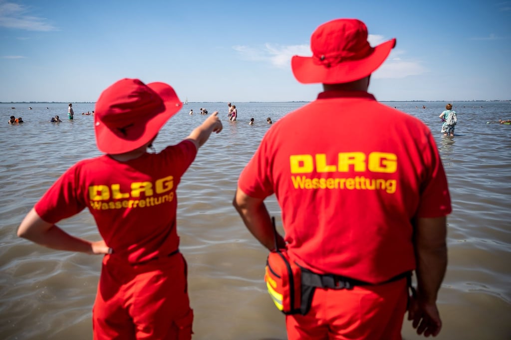 Mitglieder der DLRG (Deutsche Lebens-Rettungs-Gesellschaft) stehen am Strand von Dangast.