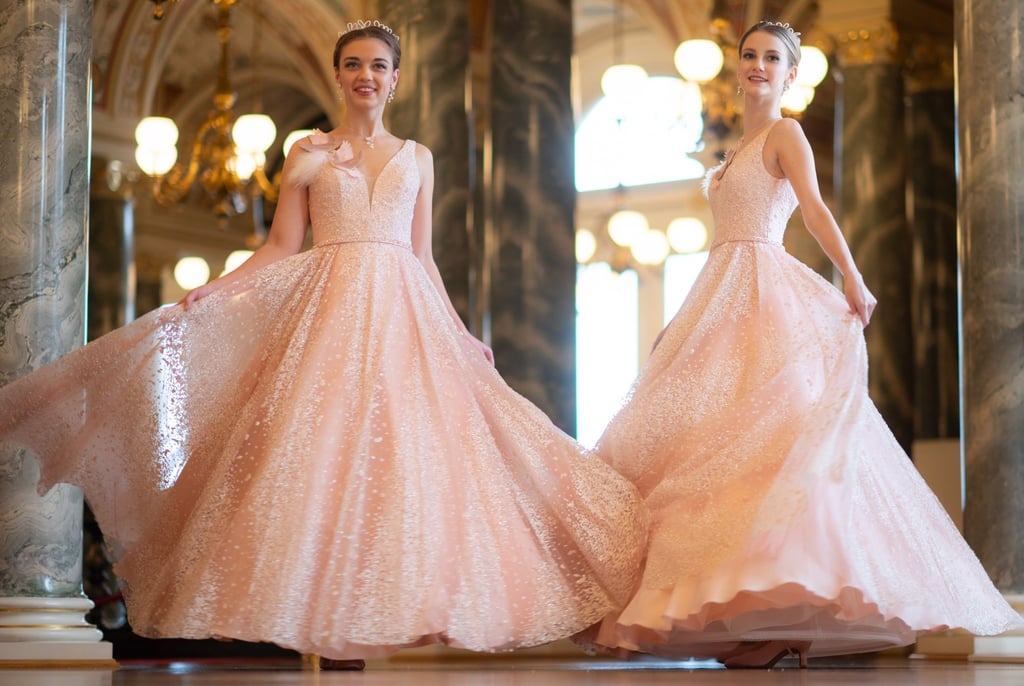 Astrid Haferland (l) und Anna-Lena Köhler, laufen bei der Vorstellung des Debütantinnenkleides für den Semperopernball 2024 im Rundfoyer der Semperoper entlang.