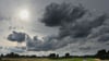Wechselhafte Wetteraussichten fürs Wochenende: Ein dunkler Wolkenhimmel über dem Radweg und Deich in der Muldeaue.