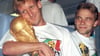 Andreas Brehme (l) mit dem WM-Pokal nach dem Finalsieg 1990 gegen Argentinien. Rechts daneben sein Mitspieler Thomas Häßler.