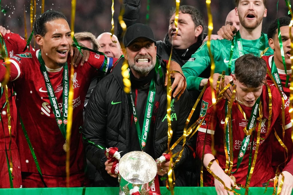 Jürgen Klopp (M) jubelt mit dem Pokal.