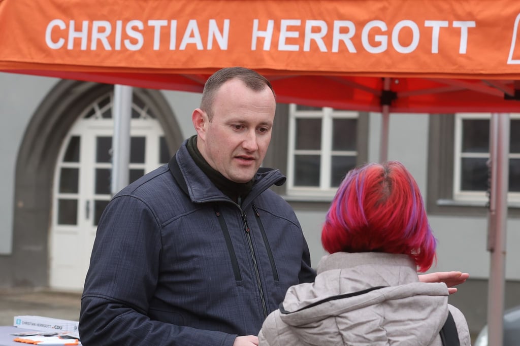 Christian Herrgott (CDU) steht an einem Wahlkampfstand.