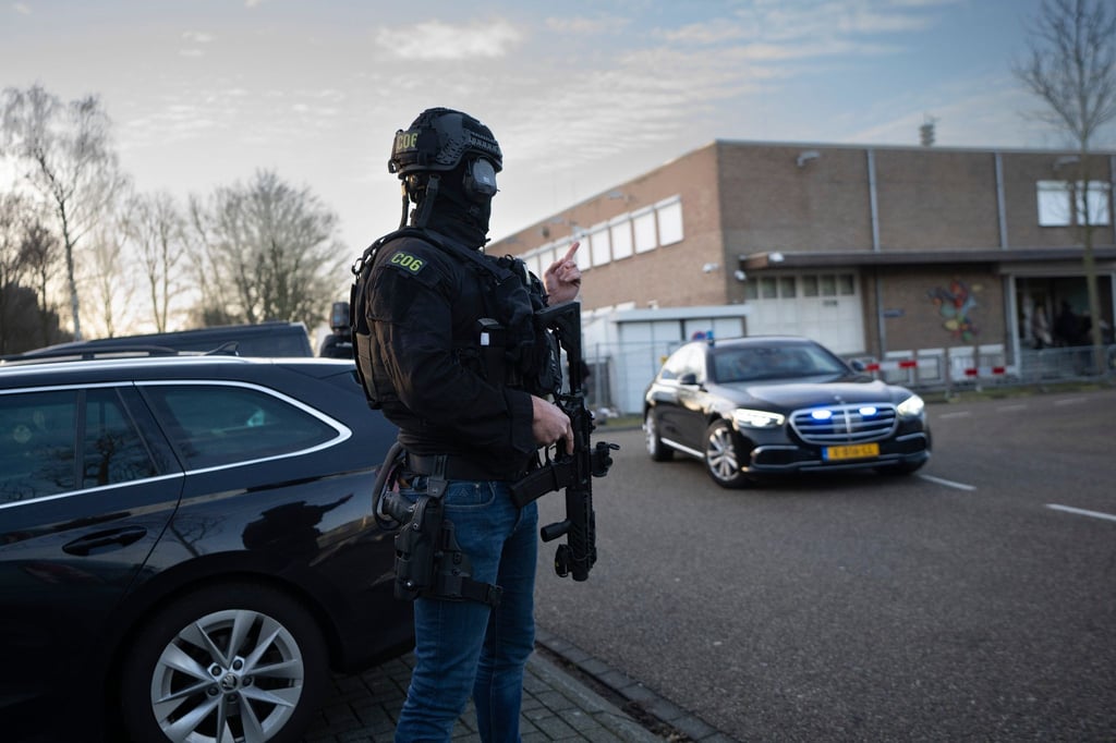 Maskierte und bewaffnete niederländische Polizisten bewachen einen Transport mit einigen der Verdächtigen, die vor dem Hochsicherheitsgebäude des Gerichts in Amsterdam eintreffen.
