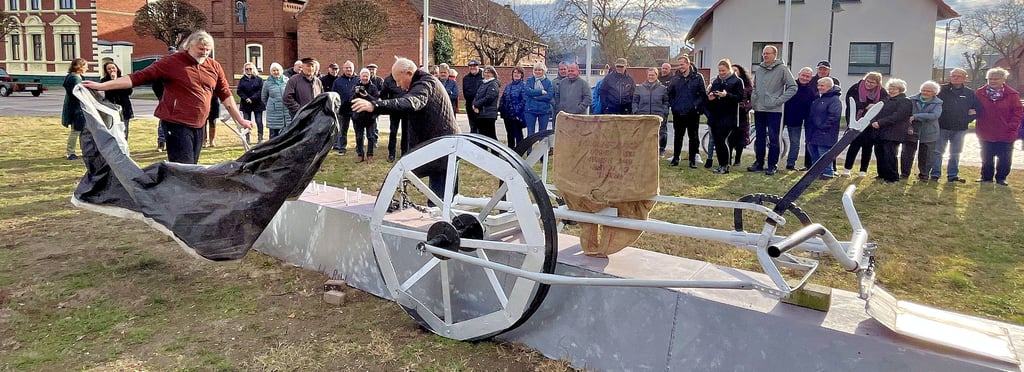 Christian Warnke und Klaus-Dieter Ruhnke enthüllen das neue Denkmal mitten im Dorf. Die „Spargelspinne“ wurde in Cobbel erfunden.