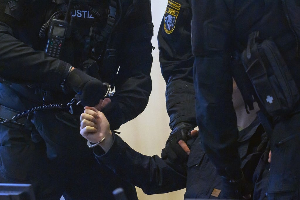 Justitzbeamte nehmen dem Angeklagten im Gerichtssaal vom Landgericht die Handschellen ab.
