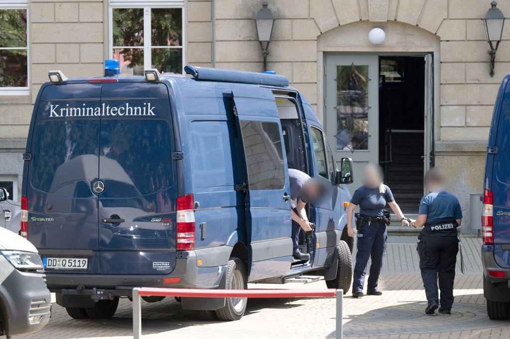 Mitarbeiter der Kriminaltechnik stehen auf dem Schulhof einer Grund- und Oberschule.