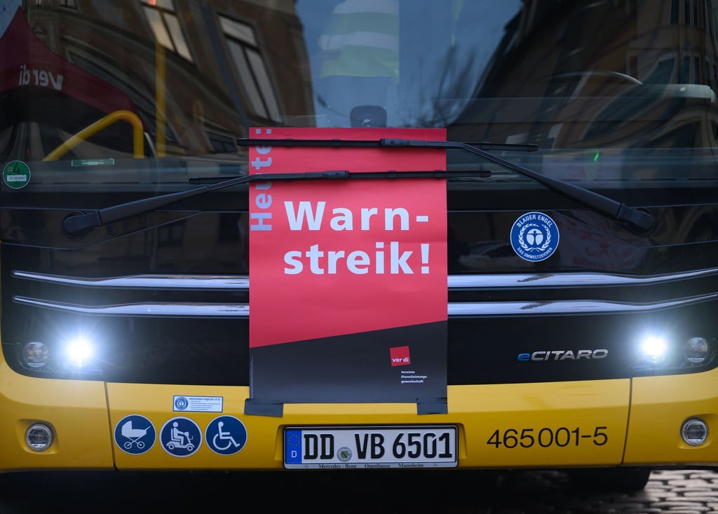 Ein Plakat „Warnstreik“ ist an einem Bus der DVB im Betriebshof Trachenberge unter den Scheibenwischer geklemmt.