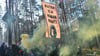Aktivisten der Initiative „Tesla stoppen“ stehen mit Rauchfackeln vor einem Transparent mit der Aufschrift „Water is a human right!“ in einem Kiefernwald nahe dem Werk der Tesla-Gigafactory Berlin-Brandenburg.