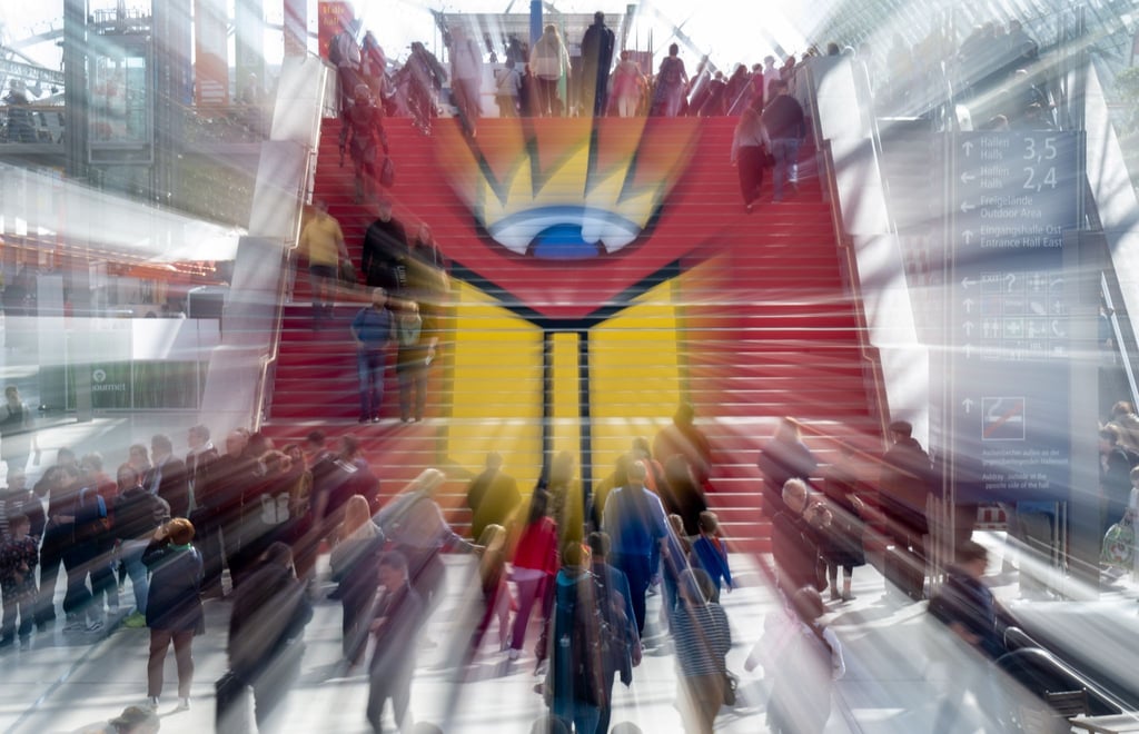 Besucherinnen und Besucher gehen über eine Treppe mit dem Logo der Leipziger Buchmesse.