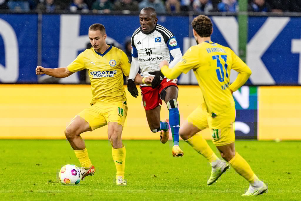 Braunschweigs Marvin Rittmüller (l-r), Hamburgs Jean-Luc Dompe und Braunschweigs Fabio Kaufmann kämpfen um den Ball. Rittmüller hat seinen Vertrag mit den Braunschweigern bis 2026 verlängert.