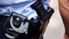 Ein Polizist trägt Handschellen und seine Dienstwaffe bei sich.
