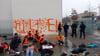Aktivistinnen und Aktivisten der Letzten Generation sitzen vor einer Wand des Bundeskanzleramts.