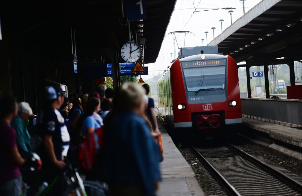 Reisende warten im Magdeburger Hauptbahnhof auf einen Zug.