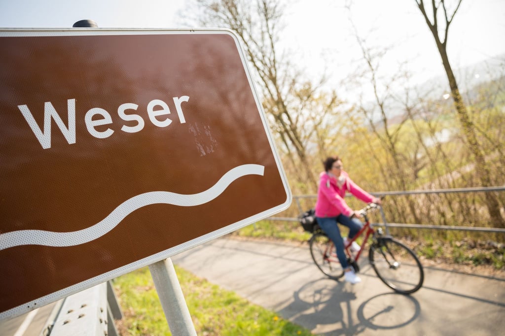 Eine Fahrradfahrerin fährt auf dem Weser-Radweg.