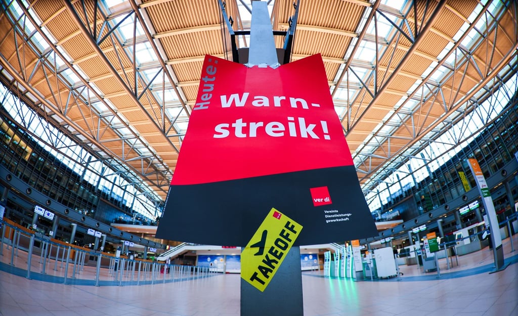 Ein Schild mit „Warnstreik“ hängt in einem Flughafen.