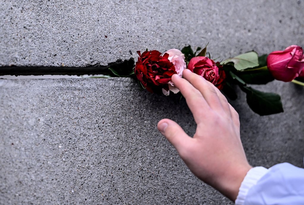 Schüler stecken bei der Zentralen Gedenkveranstaltung des 34. Jahrestags des Mauerfalls.