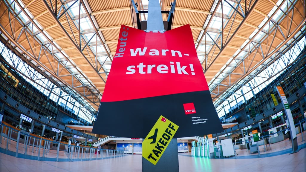 Ein Schild mit „Warnstreik“ hängt in einem Flughafen.