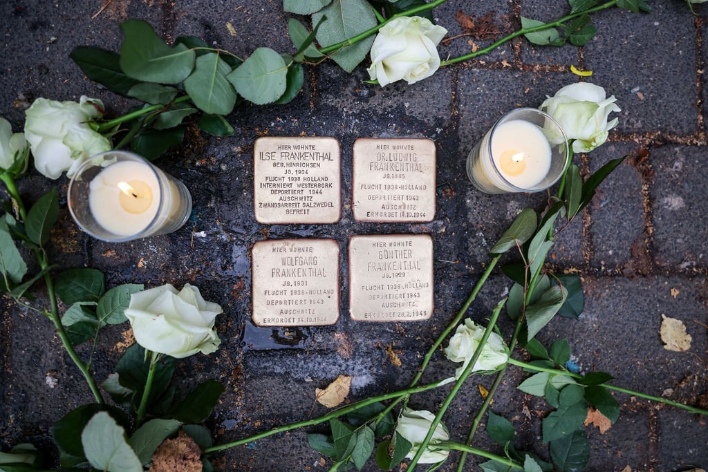 Weiße Rosen und Kerzen liegen und stehen neben den Stolpersteinen, die an das Schicksal der jüdischen Familie Frankenthal erinnern.