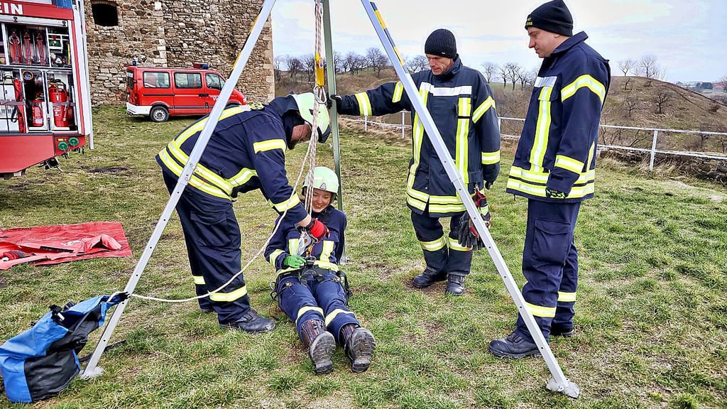 Celine Pfeil hängt bei der Übung am Rettungsgerät Rollgliss und bekommt von erfahrenden Feuerwehrmitgliedern die Technik erklärt.