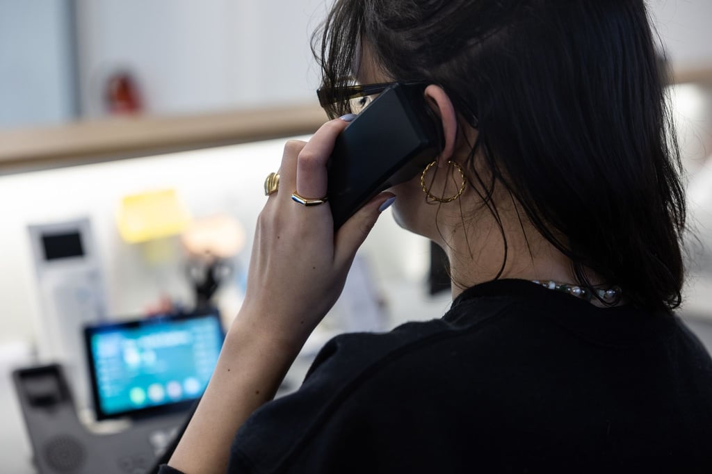 Eine Frau sitzt an einem Schreibtisch in einem Büro und telefoniert.