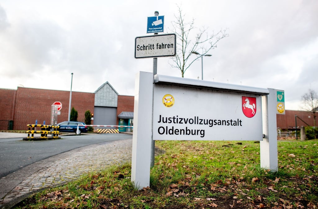 Ein Schild mit dem niedersächsischen Wappen steht vor einer Justizvollzugsanstalt.