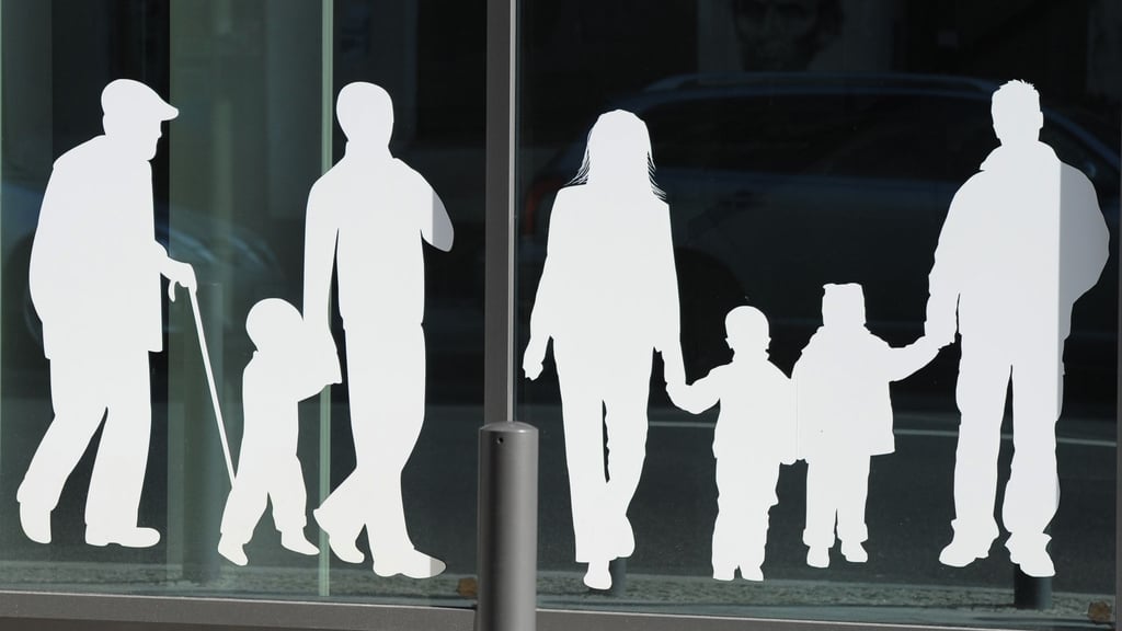 Figuren von Menschen in verschiedenem Alter sind auf Fensterscheiben aufgeklebt.