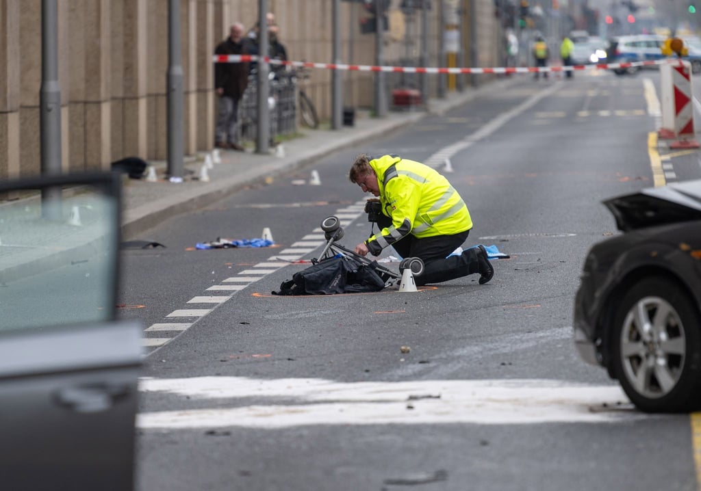 Ein Polizist kniet an der Unfallstelle neben dem zerstörten Kinderwagen.