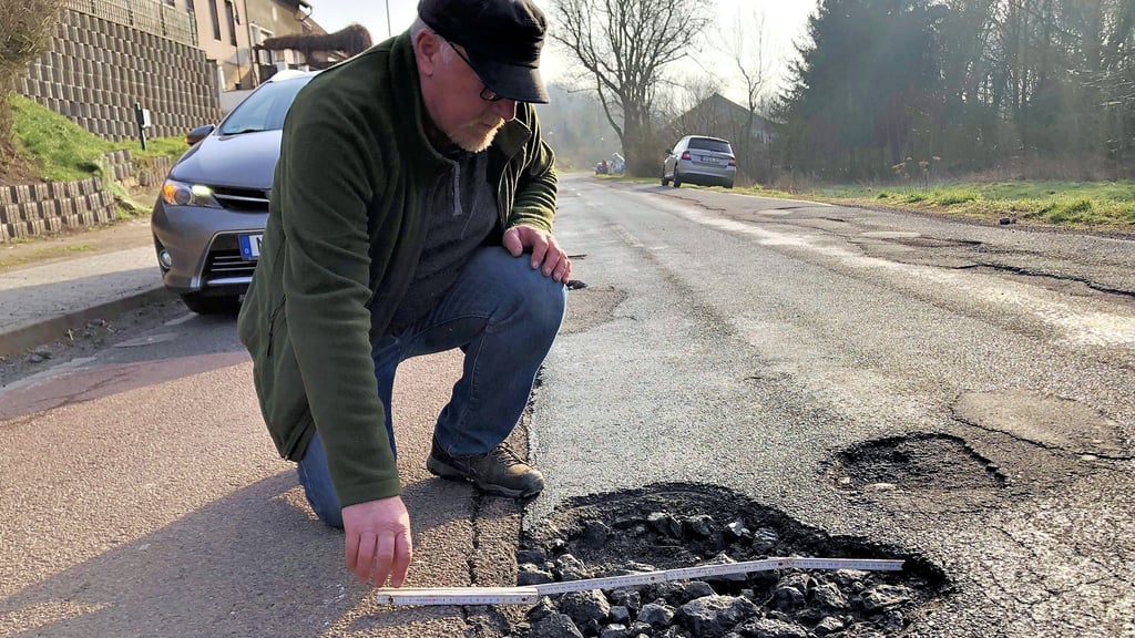 In Gerbstedt werden Schlaglöcher zum Verkehrsrisiko: Die großen Schlackesteine in den Löchern sind lose und werden zu gefährlichen Geschossen, wenn sie ungünstig unter einen Reifen gelangen. Am Straßenrand ist zu sehen, dass das häufiger passiert, denn dort liegen die Steine. Bernd Gotthardt zeigt eins der Riesenschlaglöcher.