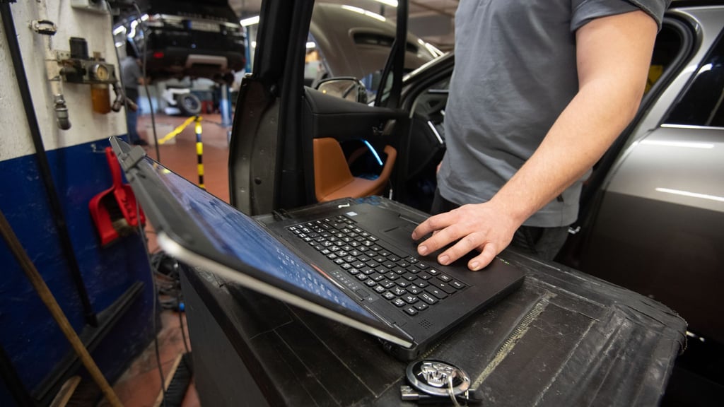 Ein KFZ-Mechaniker wartet in einer KFZ-Werkstatt einen Wagen.