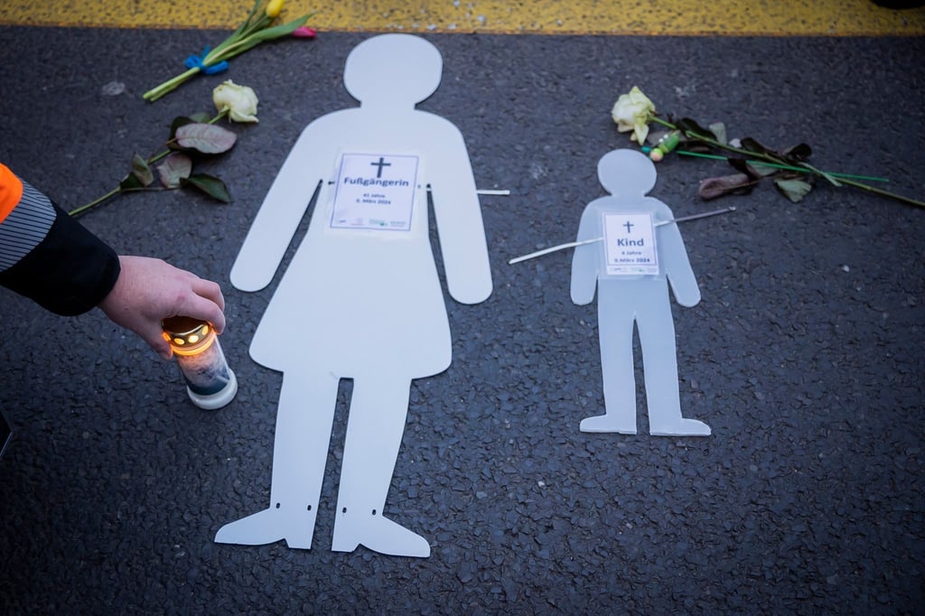 Weiße Silhouetten einer Frau und eines Kindes liegen neben Blumen und Kerzen bei einer Mahnwache auf der Leipziger Straße.