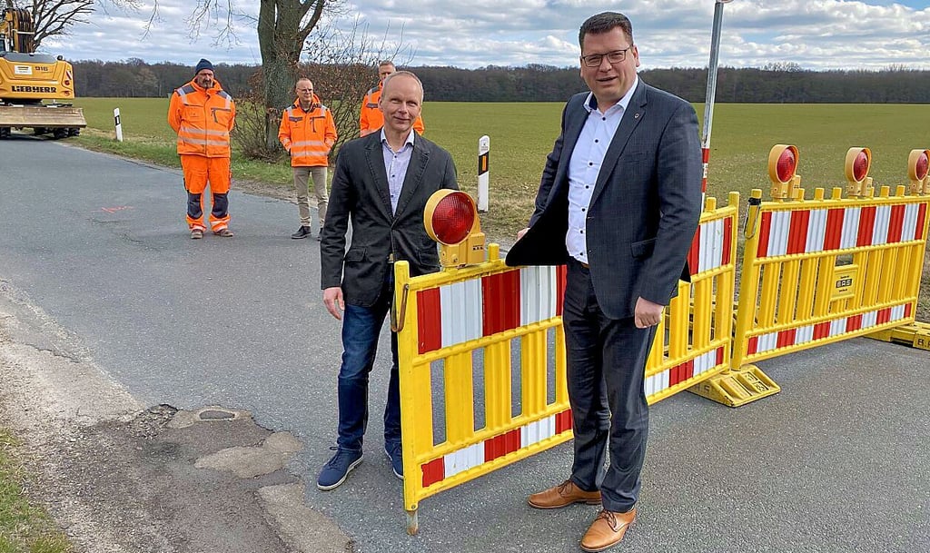 Ausschussvorsitzender Frank Brettschneider (li.) und Landrat Christian Tylsch schwenken das Sperrelement herum. Die Straßenbauarbeiten können starten.