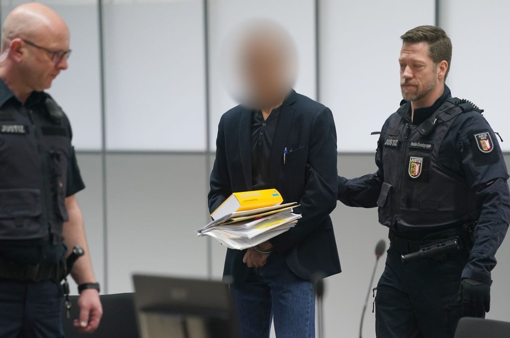 Der Angeklagte (M) wird zu Beginn des Prozesses wegen Vergewaltigung und Mord von Justizbeamten in den Gerichtssaal des Landgerichts Itzehoe im China Logistic Center gebracht.