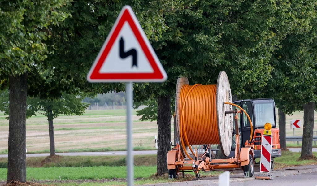 Eine Kabeltrommel mit Glasfaserkabel steht an einer schmalen Landstraße.