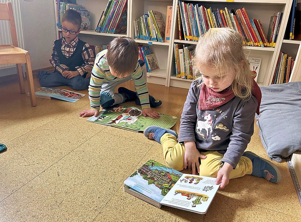Erik, Liam und Helene haben sich direkt Bücher geschnappt und schauen sich die bunten Seiten genauer an.