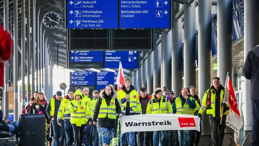 Beschäftigte der Mitteldeutschen Flughafen AG gehen während eines Warnstreiks durch den Flughafen Leipzig/Halle.