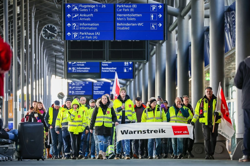 Beschäftigte der Mitteldeutschen Flughafen AG gehen während eines Warnstreiks durch den Flughafen Leipzig/Halle.