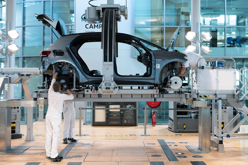 Mitarbeiter montieren in der Gläsernen Manufaktur von Volkswagen die Karosserie und den Antriebsstrang eines VW ID.3.