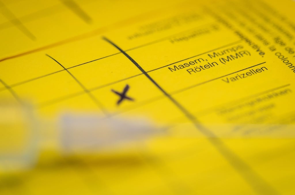 Eine Spritze liegt auf einem Impfpass in Vorbereitung auf eine Schutzimpfung gegen Masern.