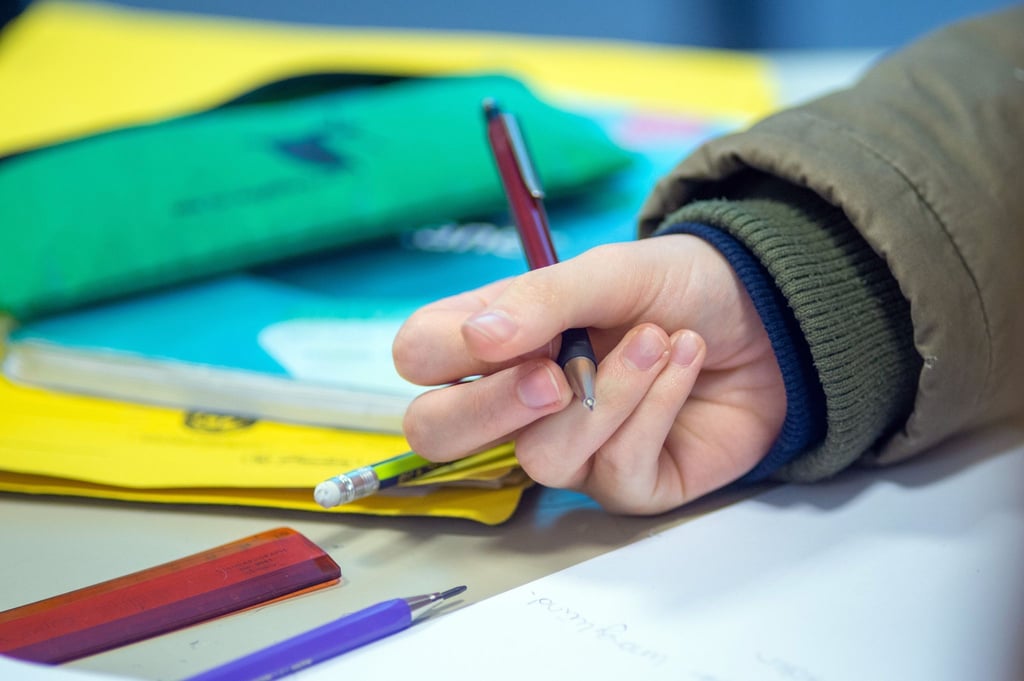 Ein Schüler schreibt im Unterricht.