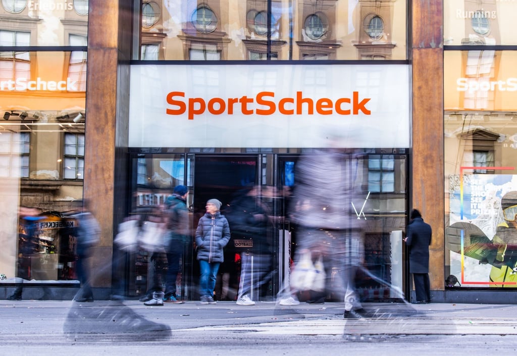 Personen gehen an einer Sportscheck-Filiale in der Münchener Fußgängerzone vorbei.