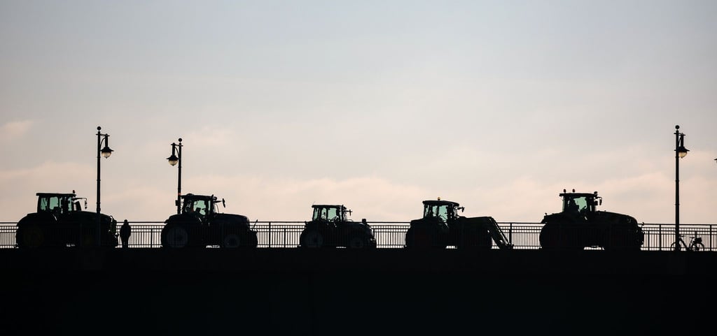 Landwirte blockieren mit Traktoren eine Brücke.