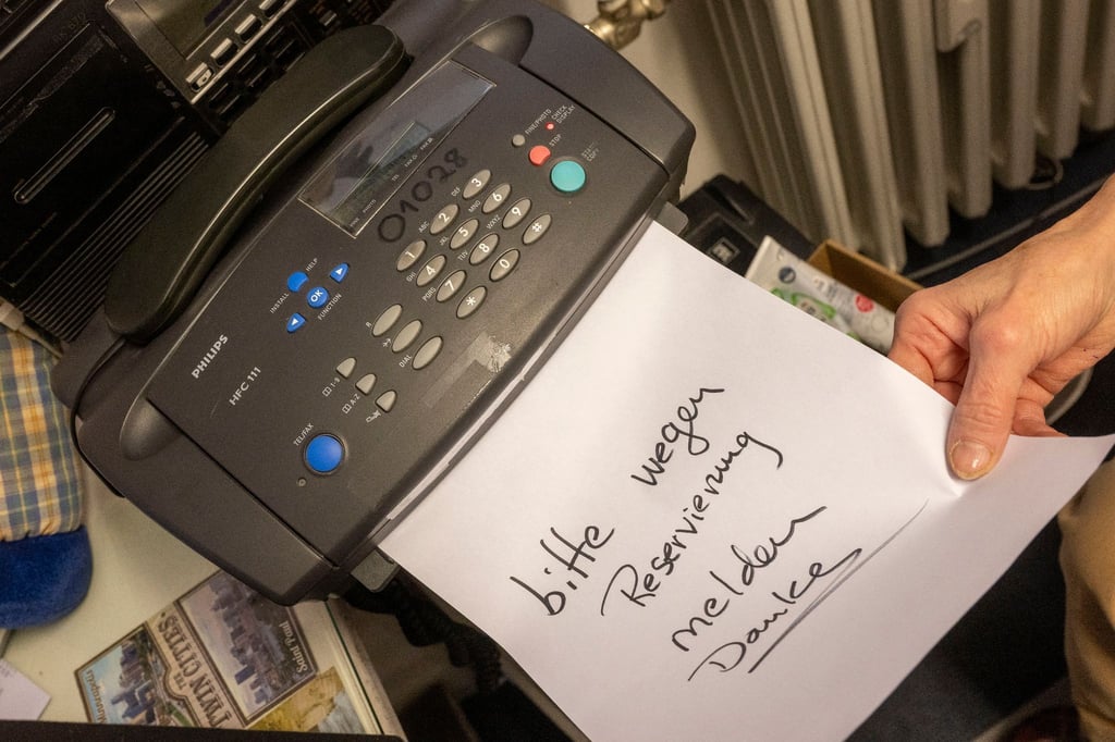 Eine Frau schiebt ein beschriftetes Papier in ein Faxgerät.