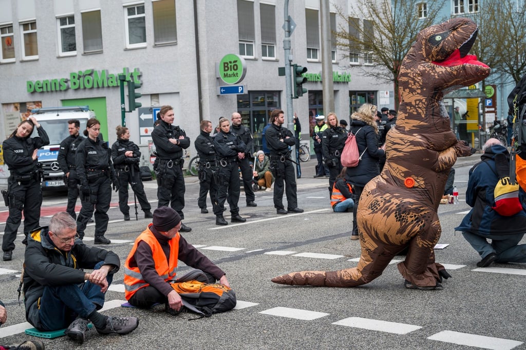 Demonstrantinnen und Demonstranten, die auf der Straße sitzen, blockieren die Kreuzung.