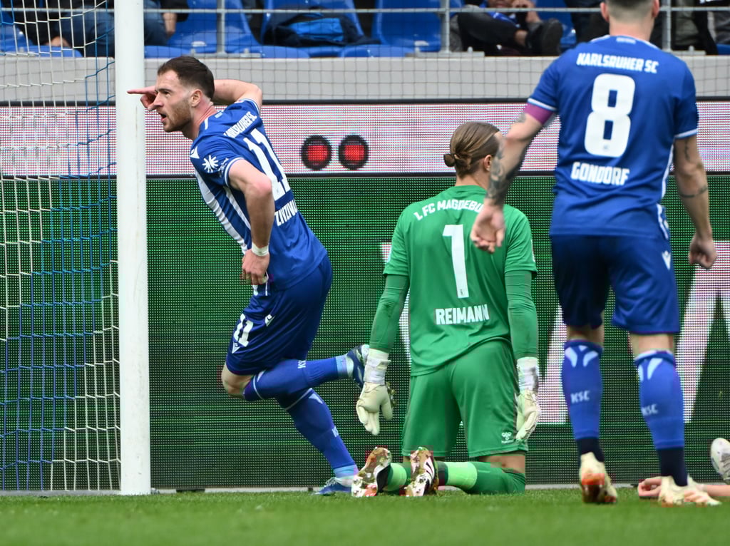 Der Karlsruher Budu Zivzivadze (r) bejubelt seinen Treffer zum 3:0. Rechts ist der Magdeburger Torwart Dominik Reimann zu sehen.