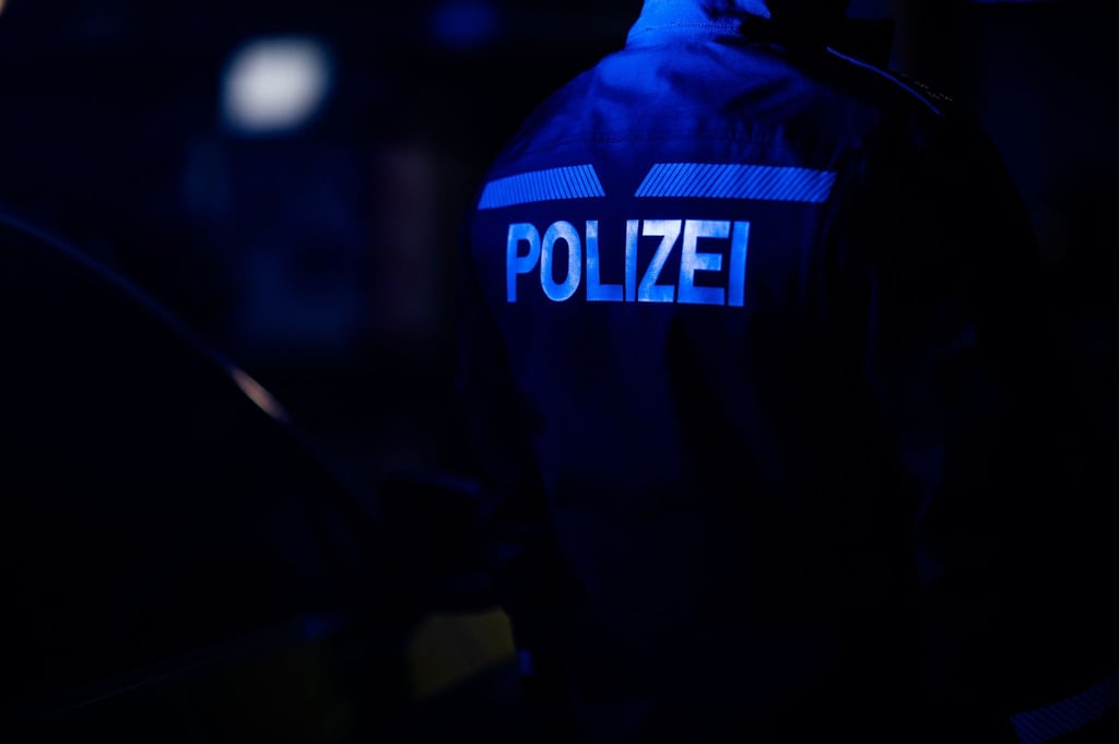 Ein Polizist steht neben einem Polizeiauto.